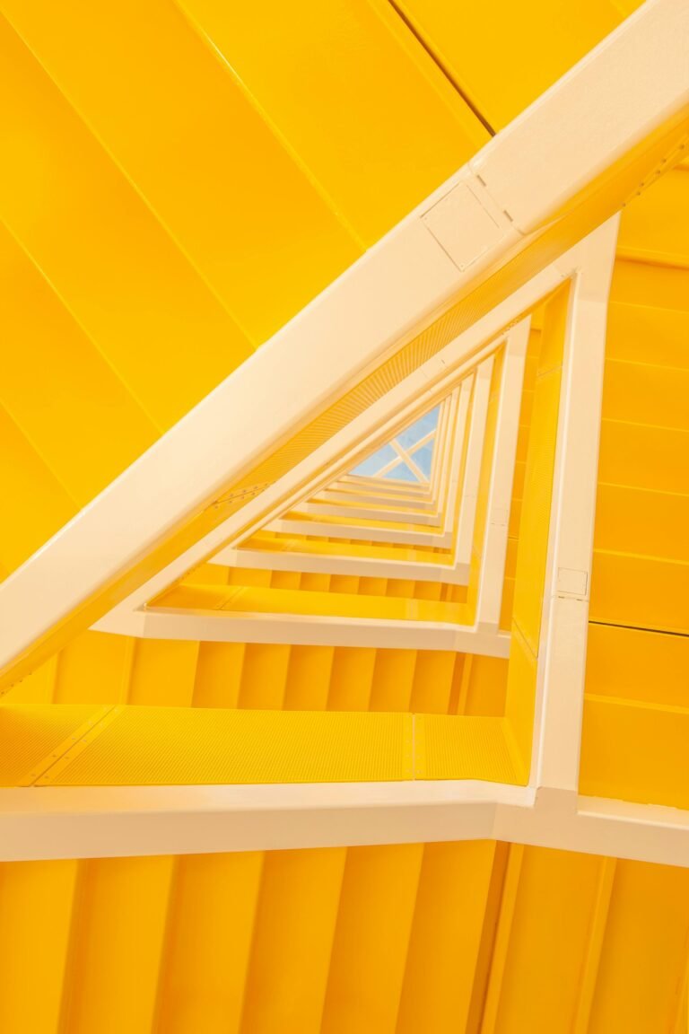 From below of modern geometric staircase made of yellow painted wooden panels inside modern house